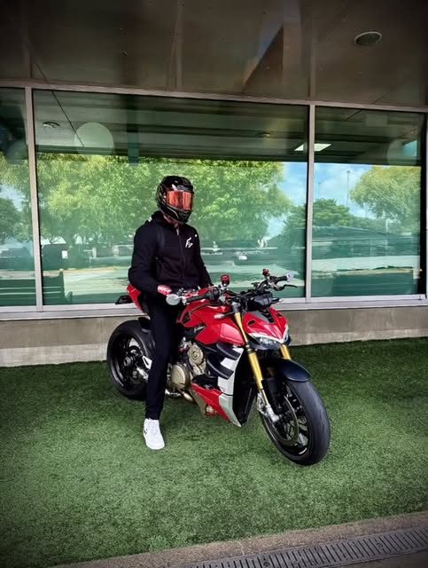 Jasper on a motorbike outside a glass building